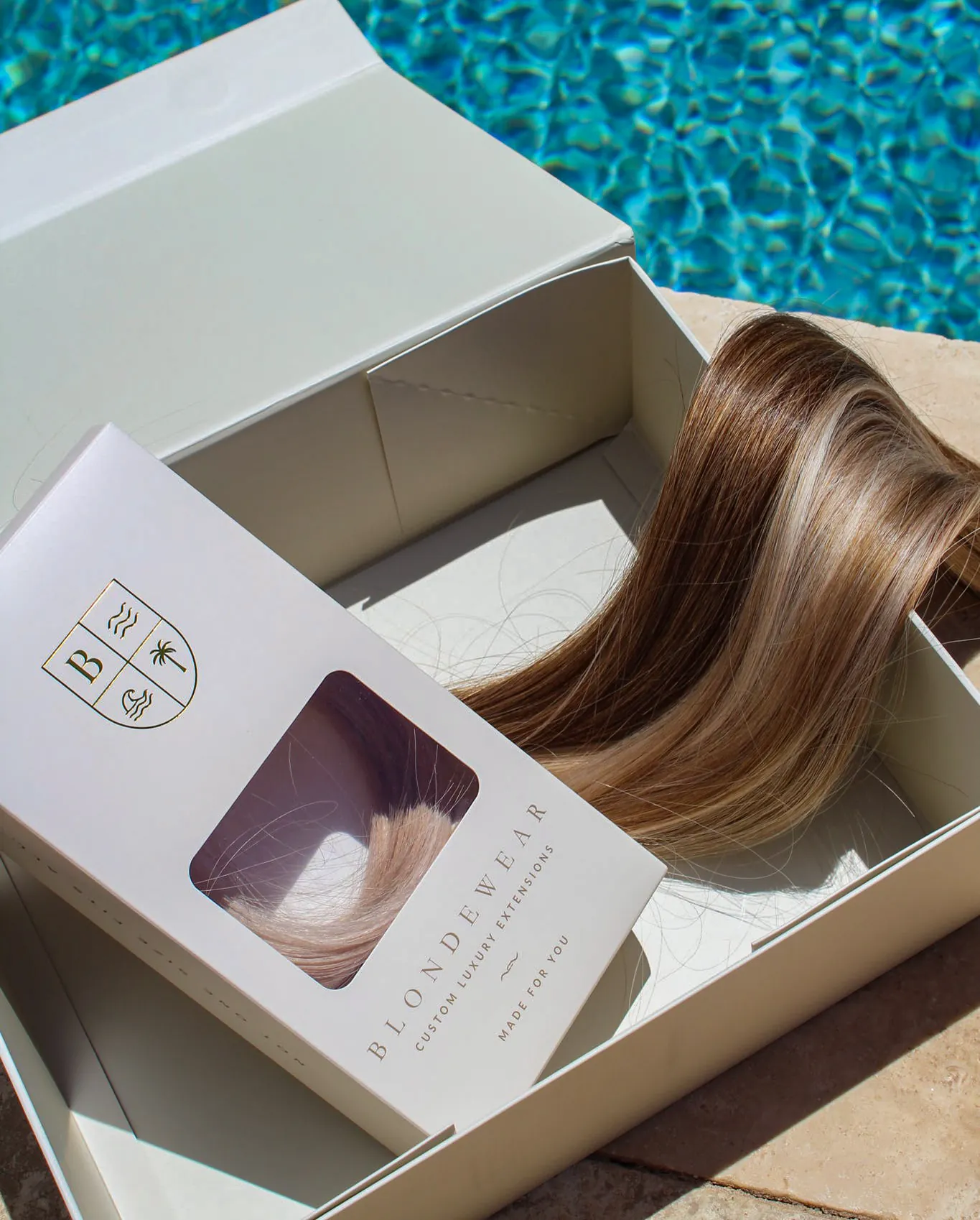 An open BlondeWear box by a pool, a length of blended brunette and blonde hair inside