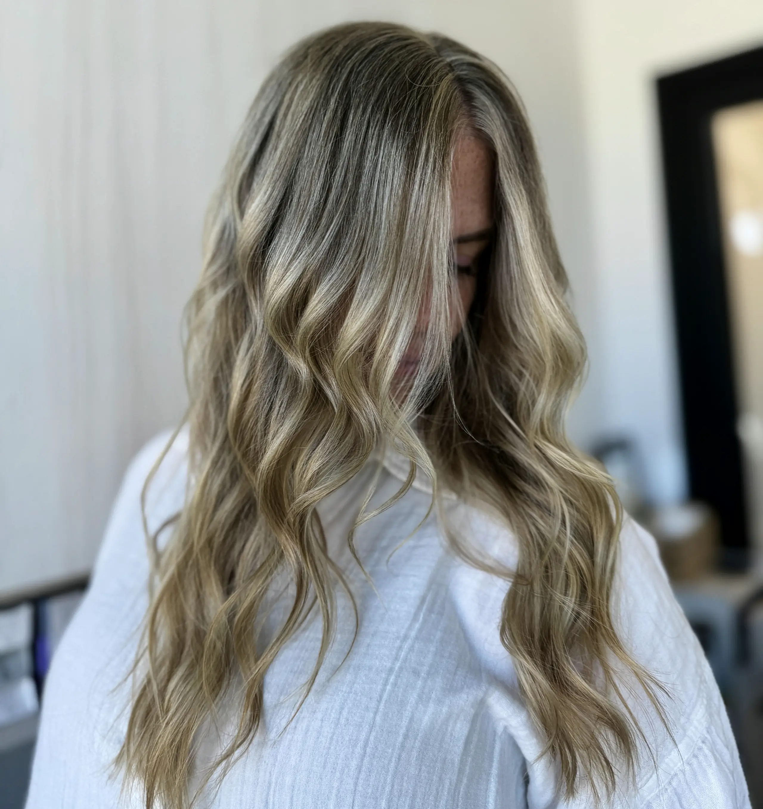 Soft buttery blonde waves falling over a white shirt