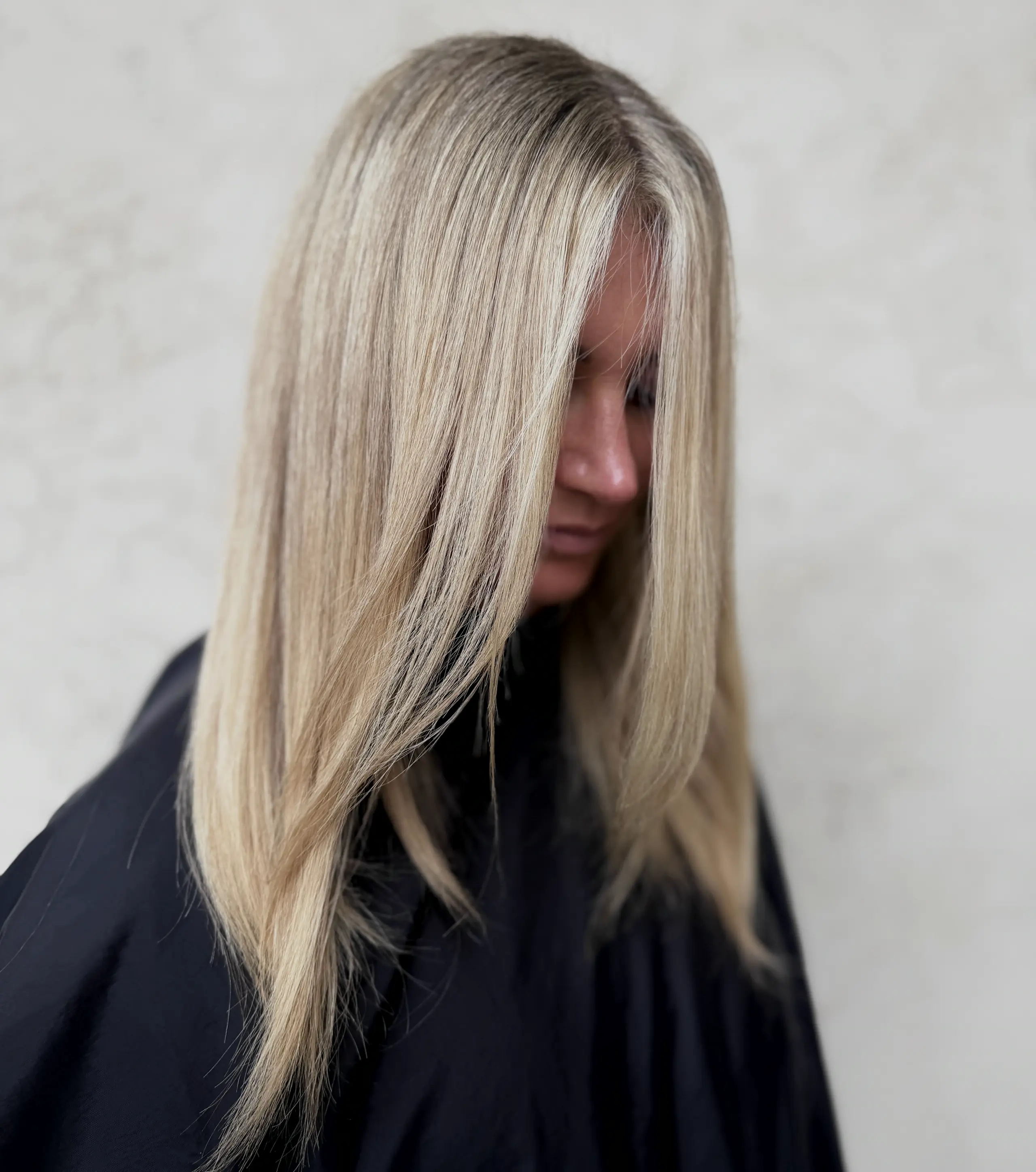 Sleek platinum blonde in profile, in a black cape
