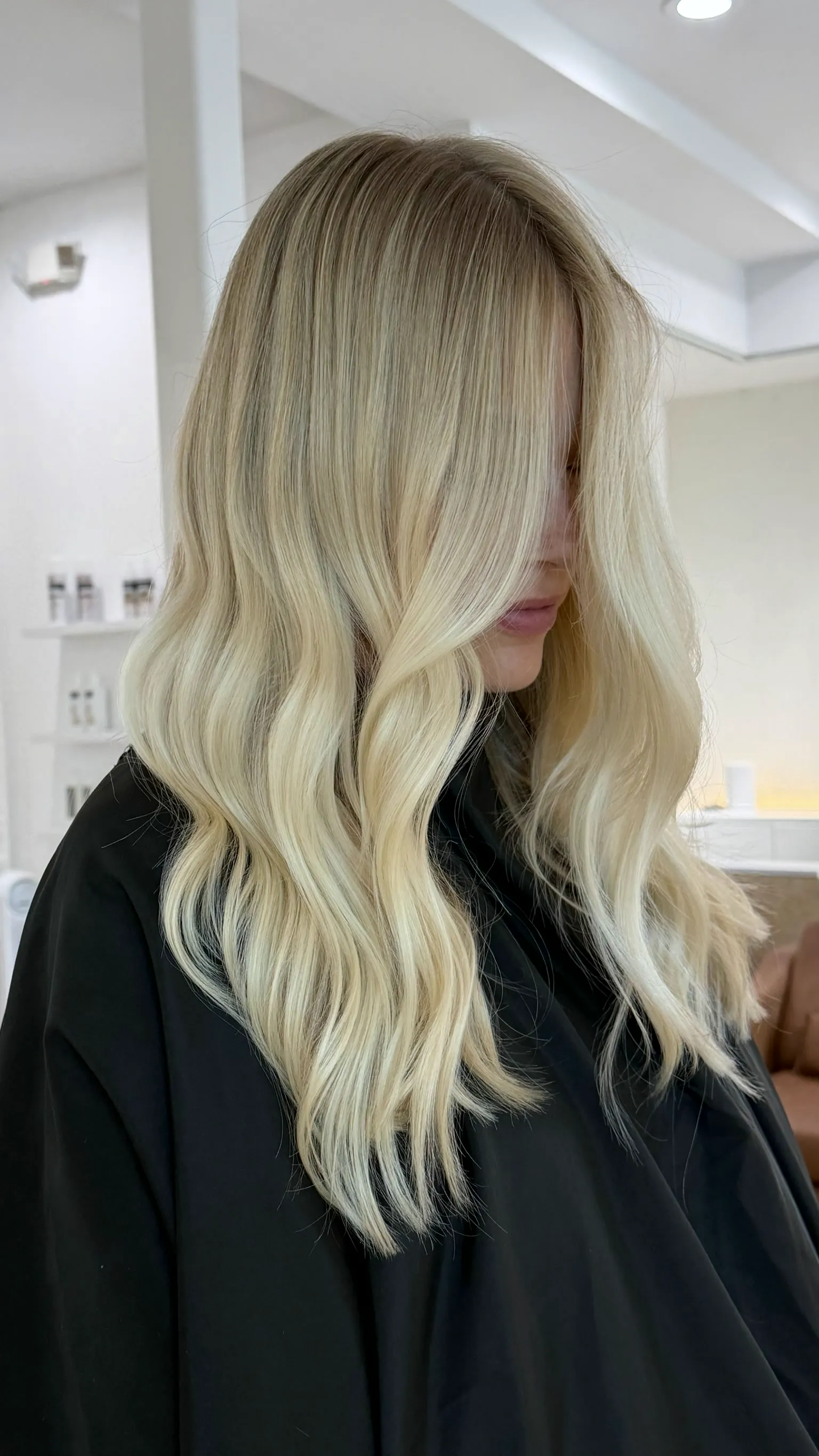 Bright blonde waves over a black cape, fresh from the chair