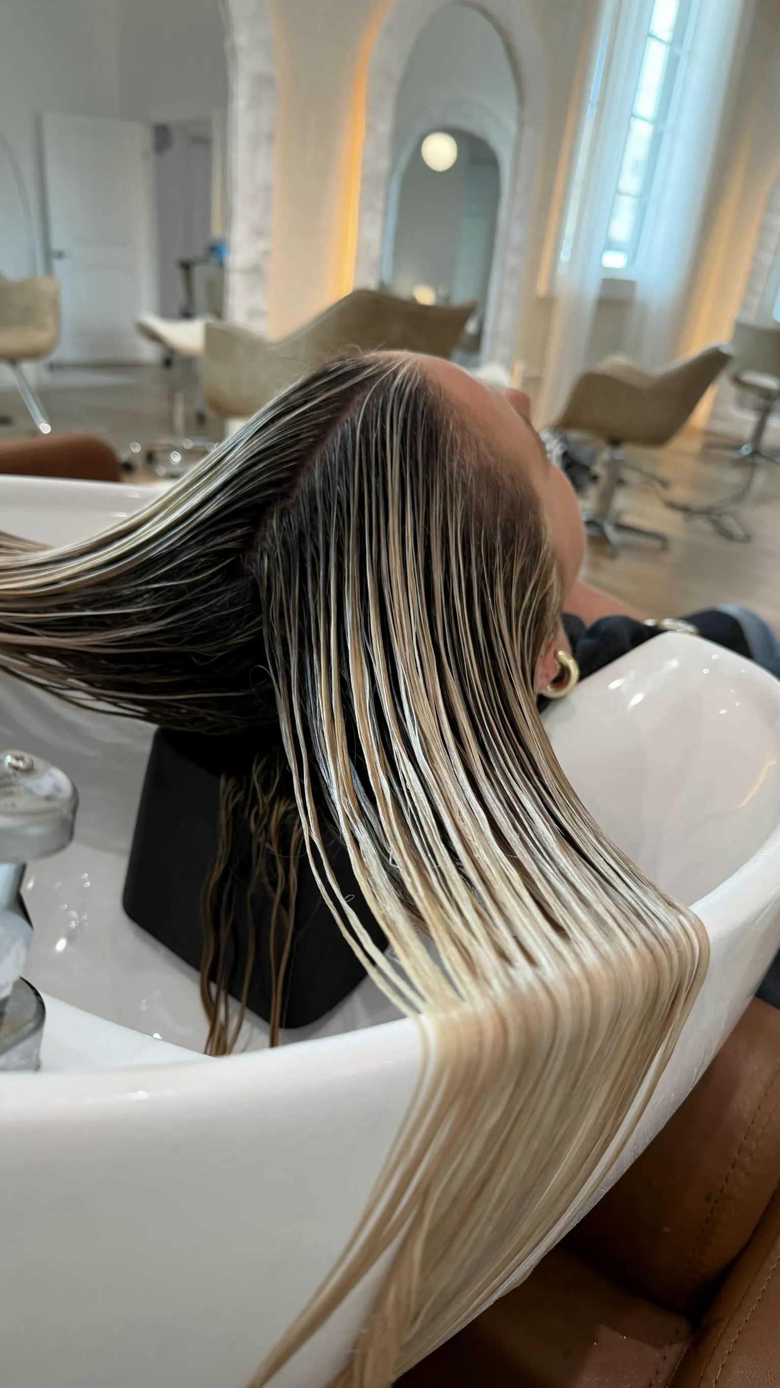 Freshly lightened hair laid across the shampoo bowl for toner